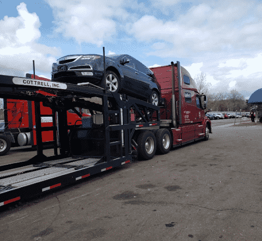 Car carrier trailer hauling a black passenger car.