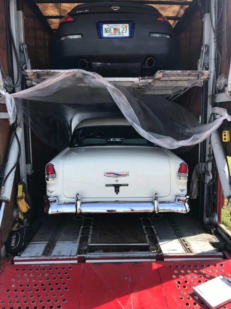 classic cadillac back view and nissan 350z back view in a closed trailer