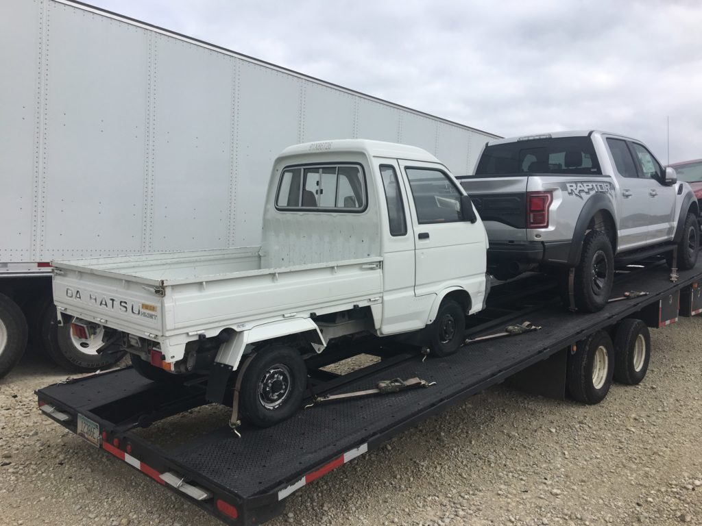 white and silver truck on open trailer