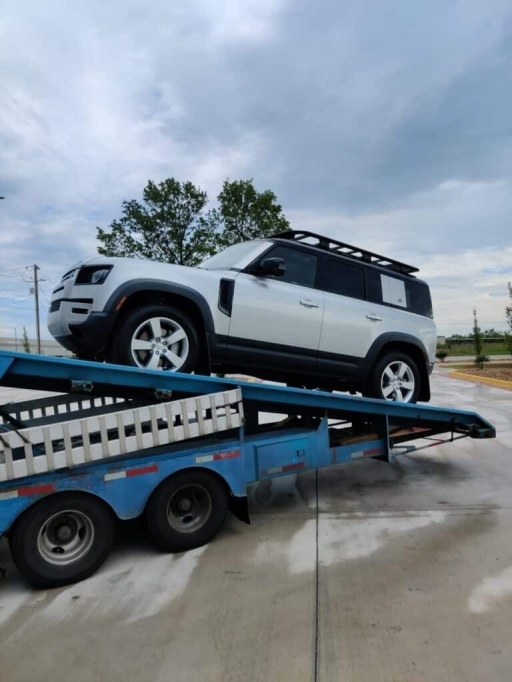 white land rover on open trailer