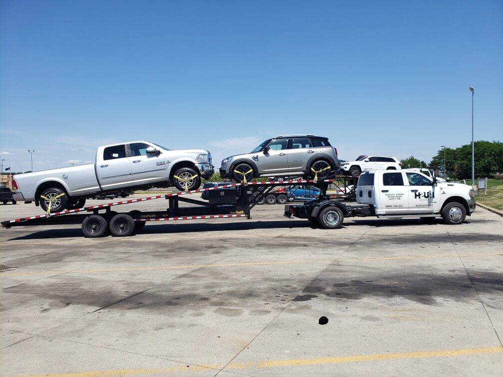 two cars on angled trucking trailer for auto transport