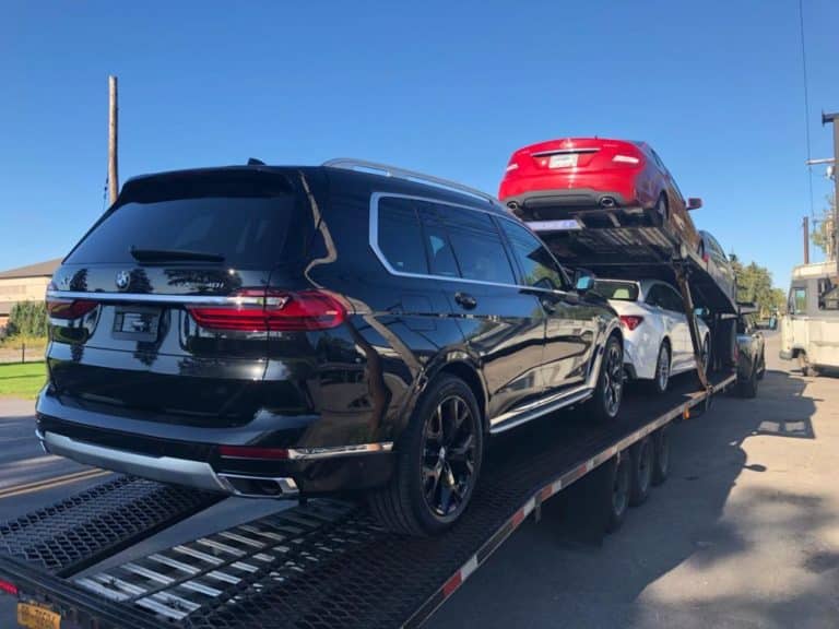 black bmw beig loaded onto trailer for transport shows the advantages of using an auto transport company