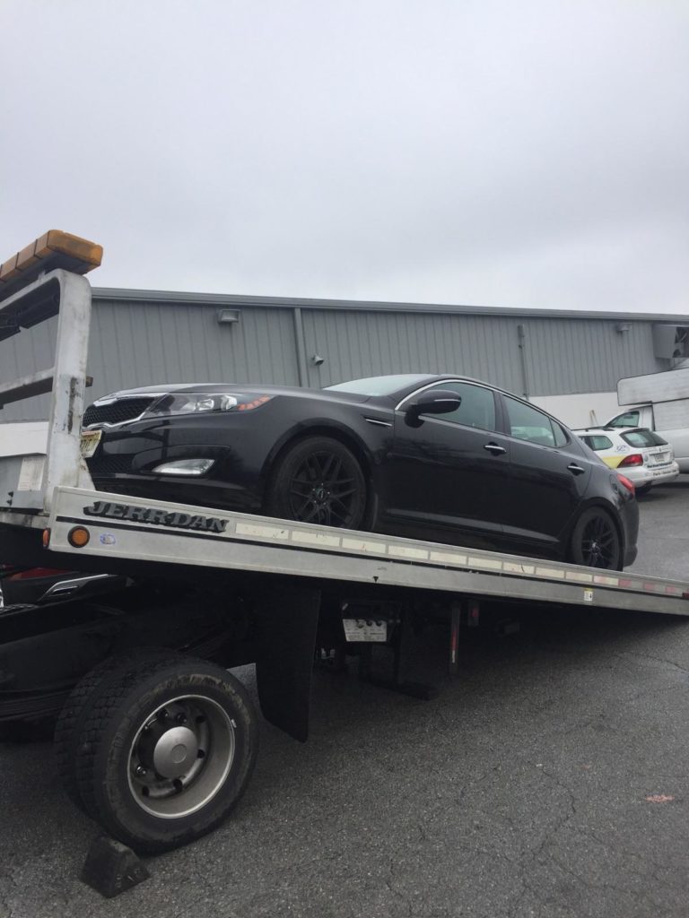 black kia car on top of logistics ramp