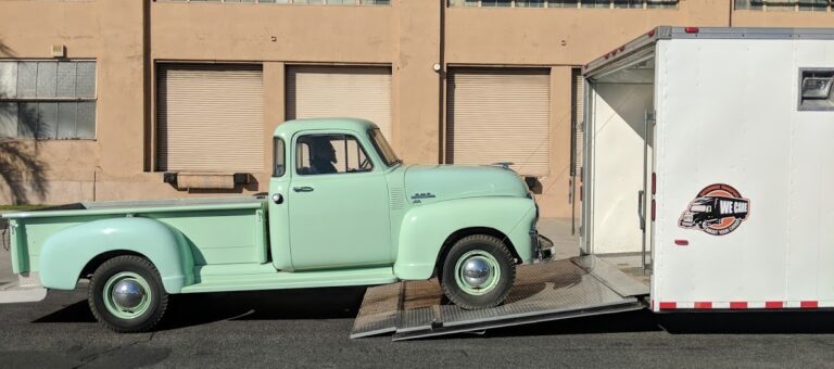 classic GMC truck being transported onto closed trailer with NTS logo on trailer