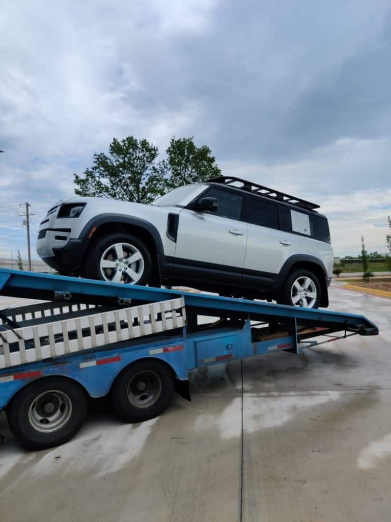 white land rover on open trailer