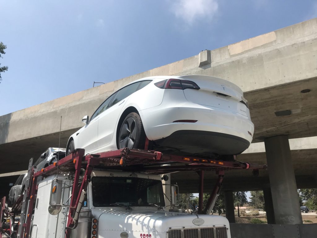white tesla on vehicle trailer for auto transport