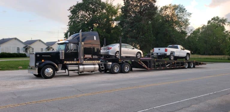 two vehicles back to back on stepdeck trailer for auto transport
