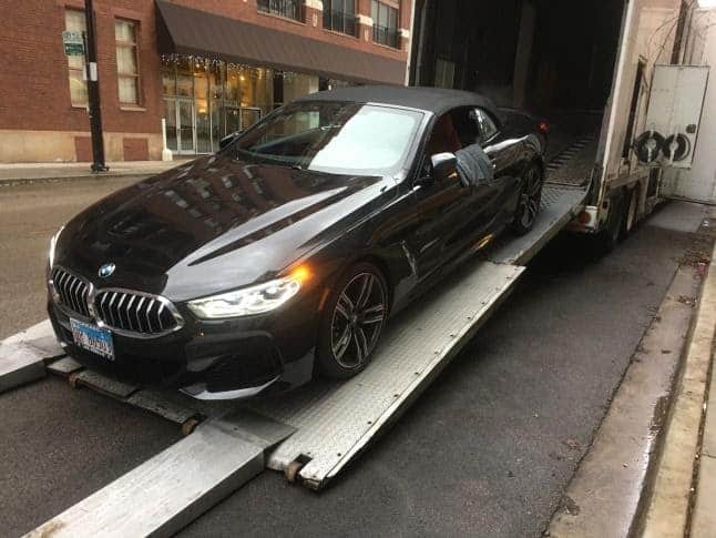 black bmw loading on an enclosed trailer