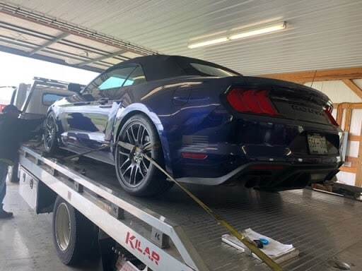 blue ford mustang on tow truck