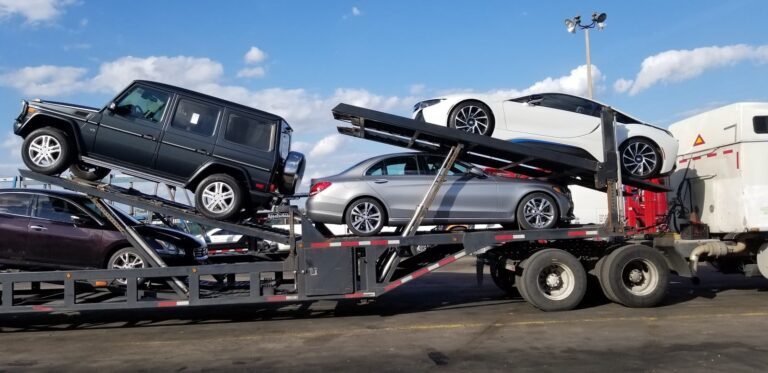 Car carrier truck holding several cars of different models on a sunny day.