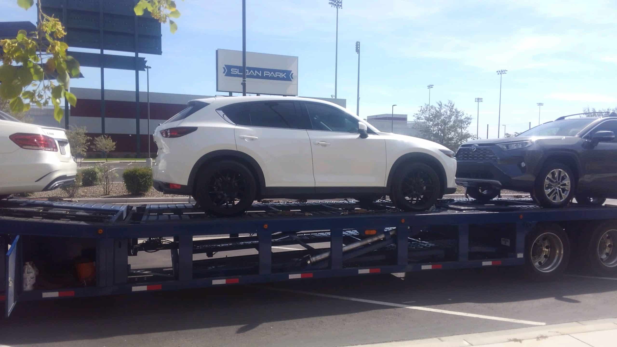 white mazda suv on stepdeck trailer for auto transport