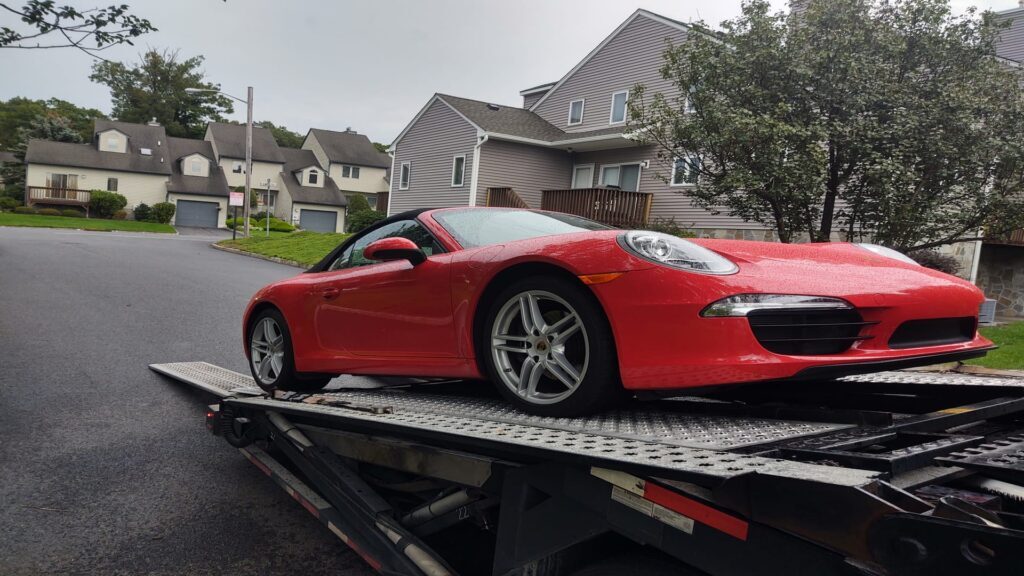 red porsche being transported on an open trailer