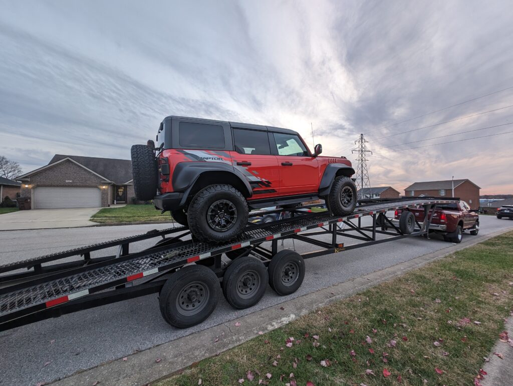 red ford raptor on open carrier