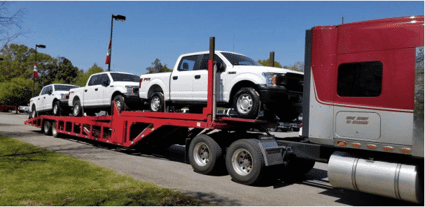 multiple ford trucks on open trailer