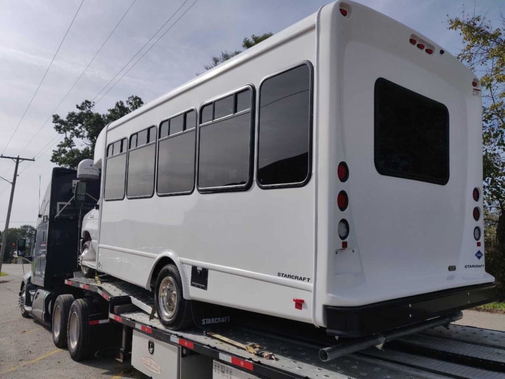 white electric shuttle bus being transport by our Kentucky driveaway services