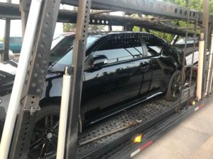 all black sedan being hauled on multi car trailer, one of the advantages of using an auto transport company