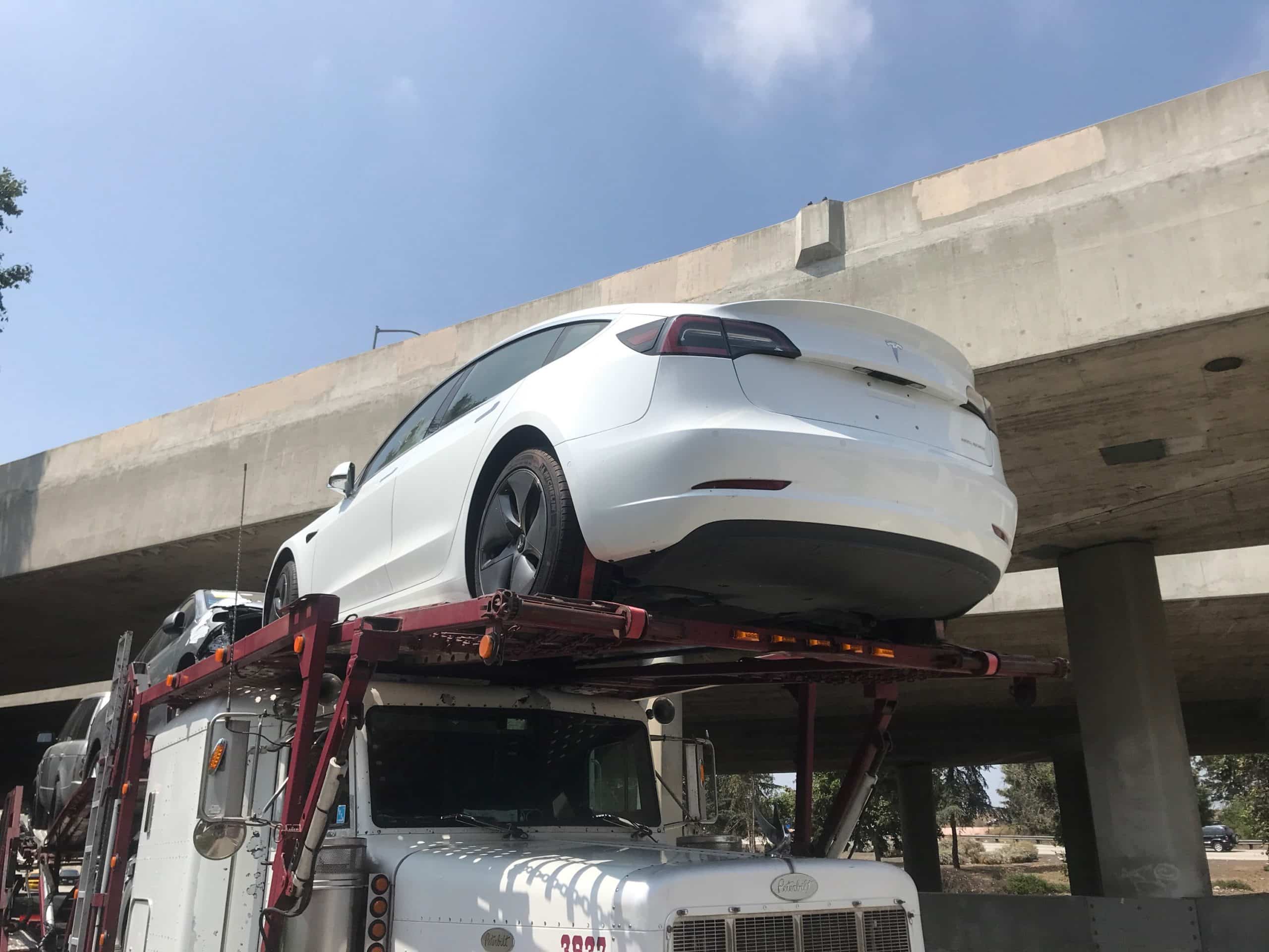 white tesla on vehicle trailer for auto transport