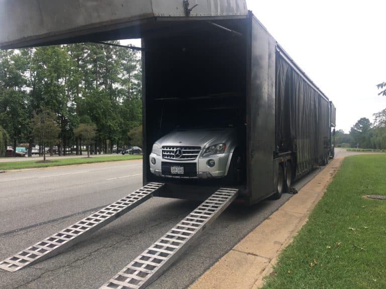 silver mercdes exiting full black enclosed trailer auto transport