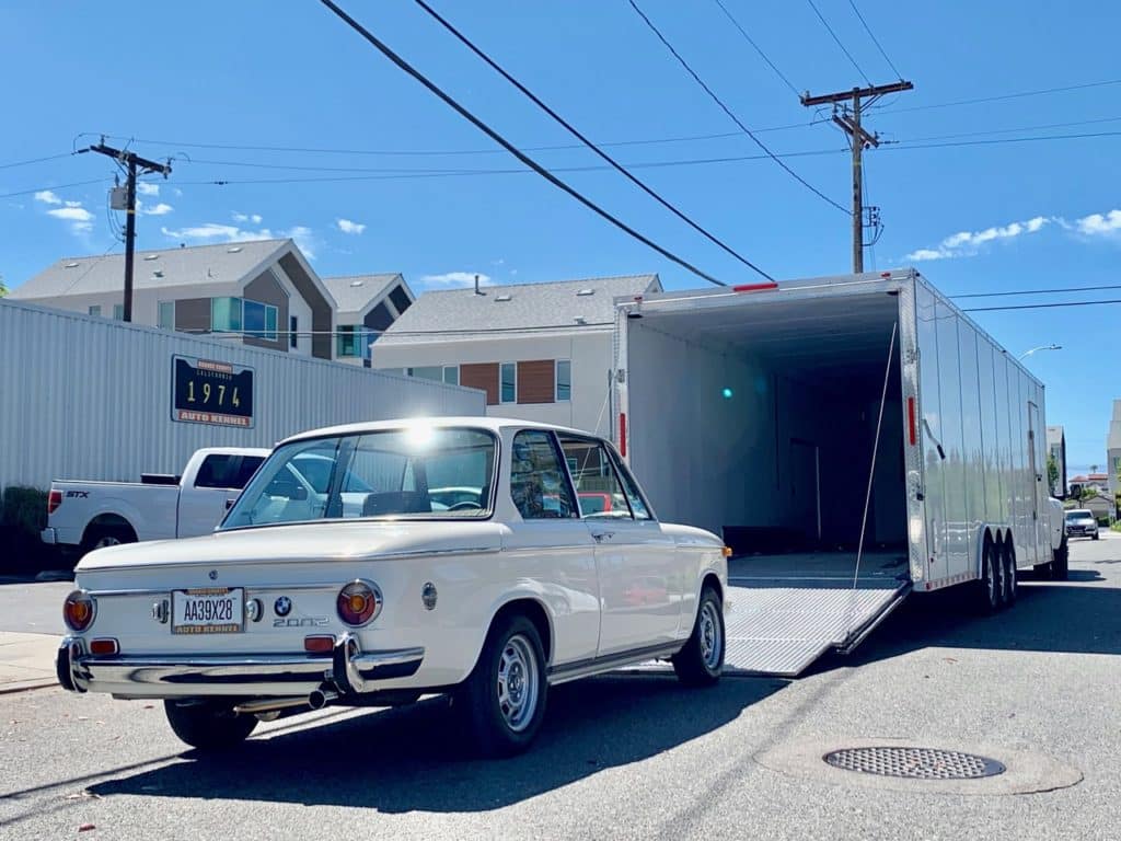 cream volored bmw going into enclosed trailer for auto transport