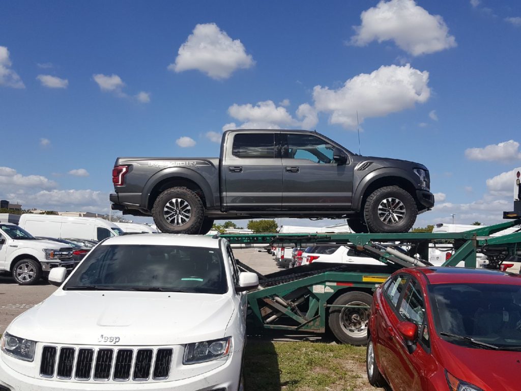 silver raptor truck on trailer for auto transport