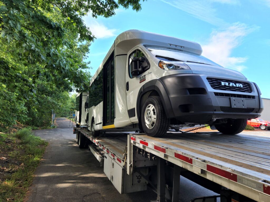 two white shuttle buses being transported