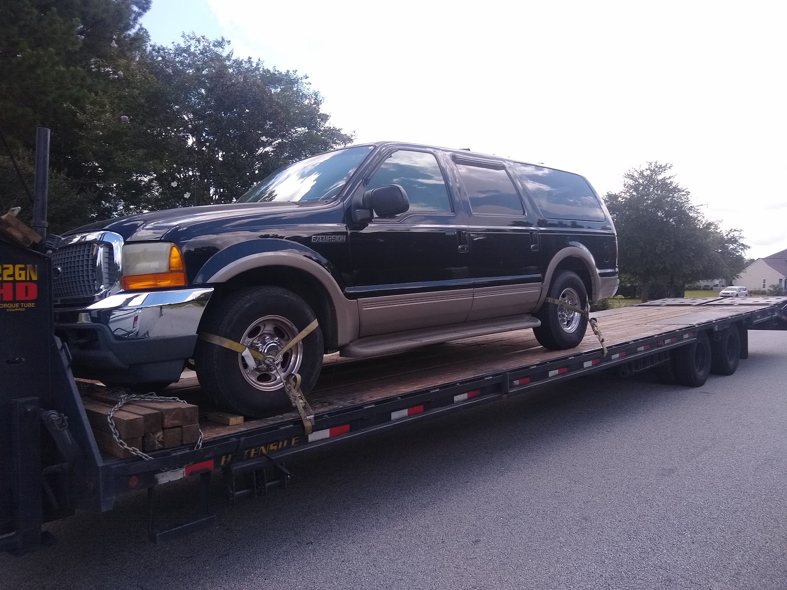 black ford excursion on flatbed trailer