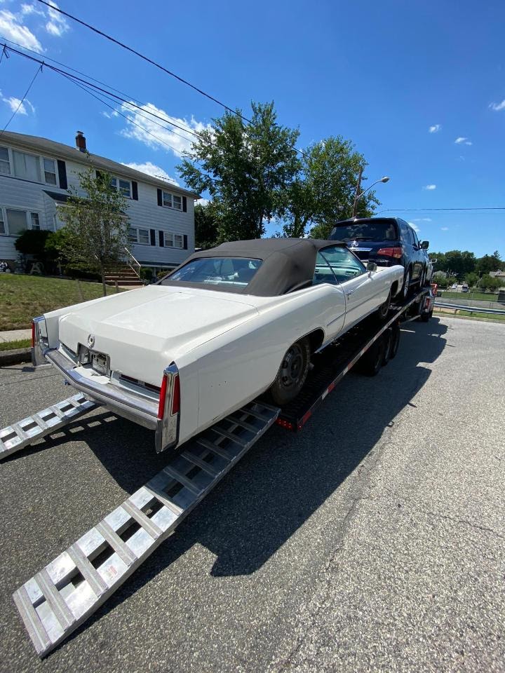 white cadillac el dorado on small open trailer