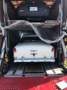 classic cadillac back view and nissan 350z back view in a closed trailer