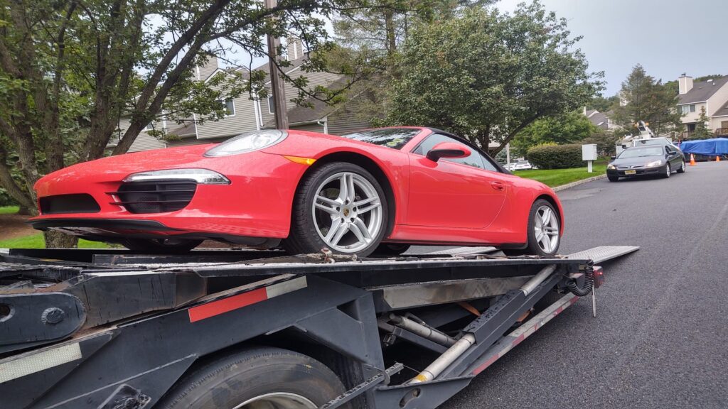 red porsche being transported on an open trailer