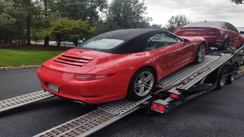 red porsche being transported on an open trailer