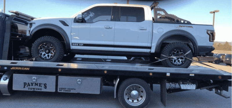 white ford raptor truck on car shipping trailer